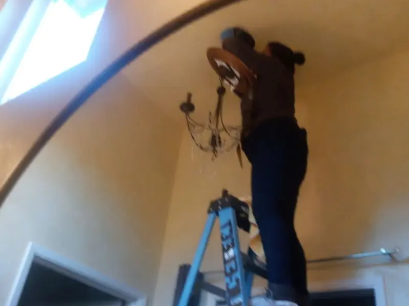 Electrician installing a chandelier in a Sherman residence